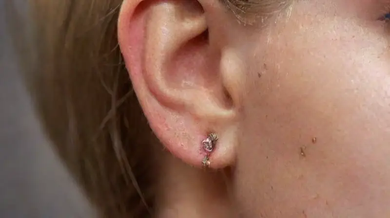 Close-up of realistic metallic ear piercings