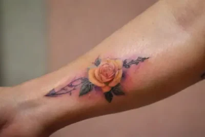 Detailed arm tattoo with vibrant watercolor background